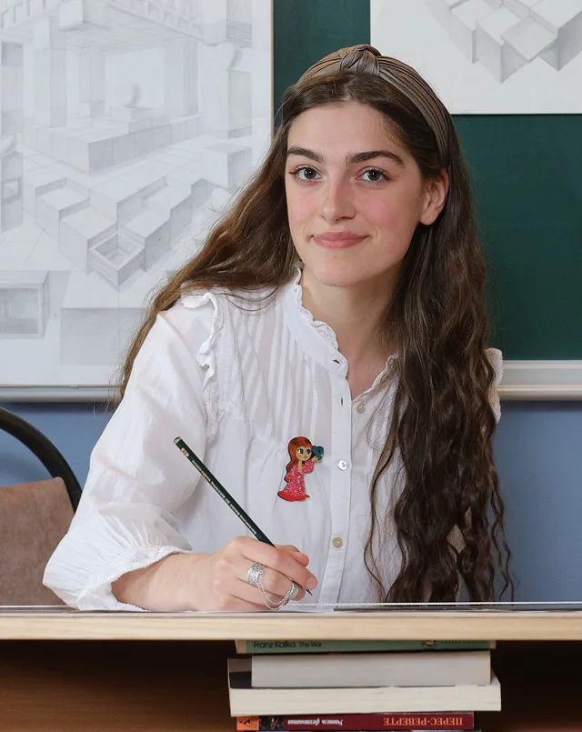 Woman in a white blouse holding a pencil at a desk
